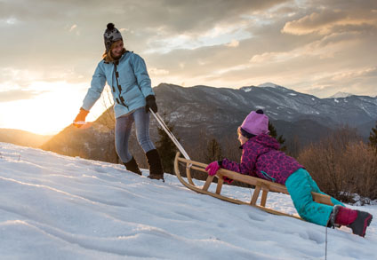 Woman pulling child up a hill on a sled